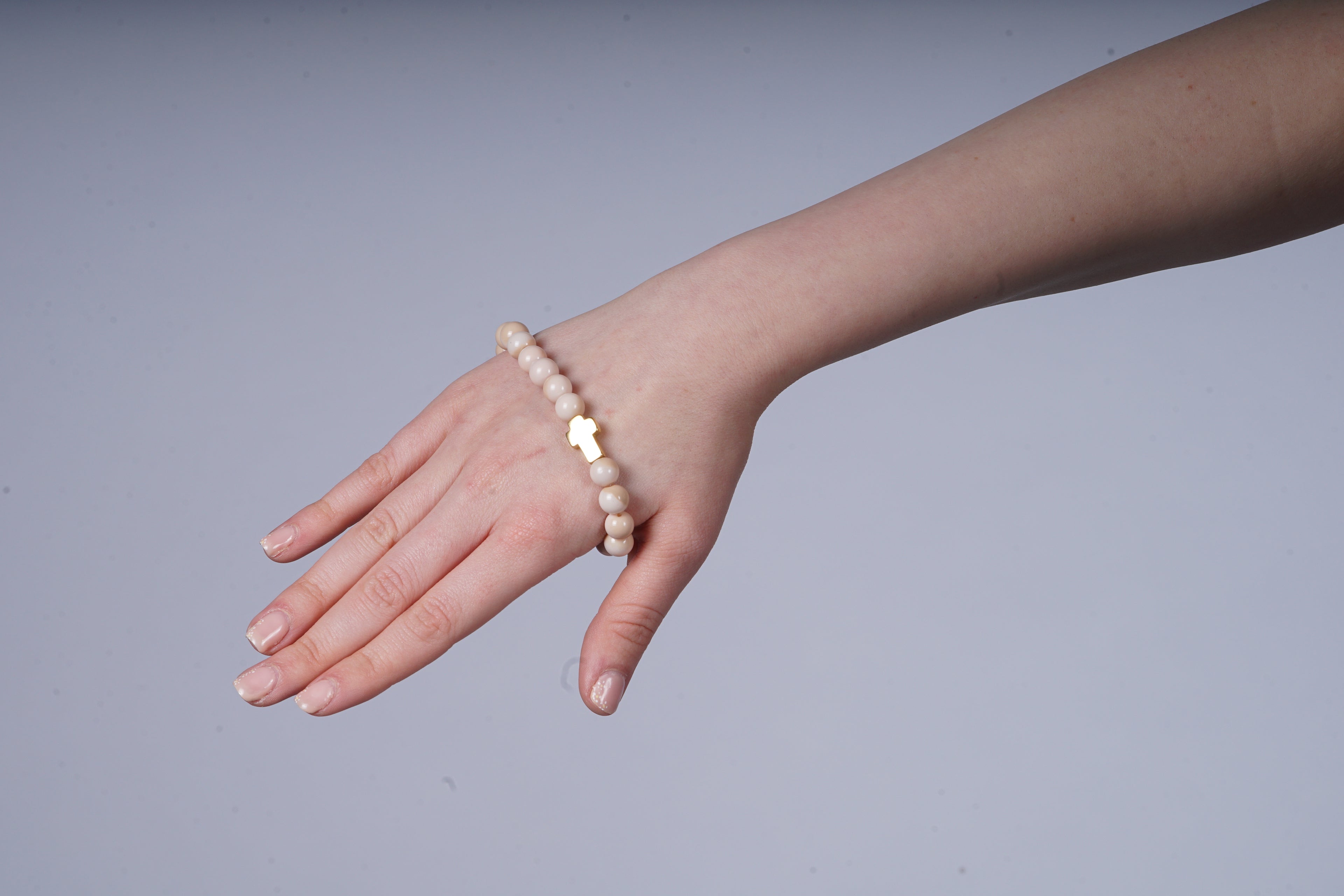 Beige armband met een kruis bedel