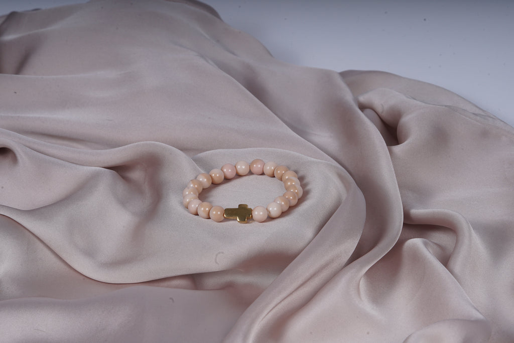 Beige armband met een kruis bedel