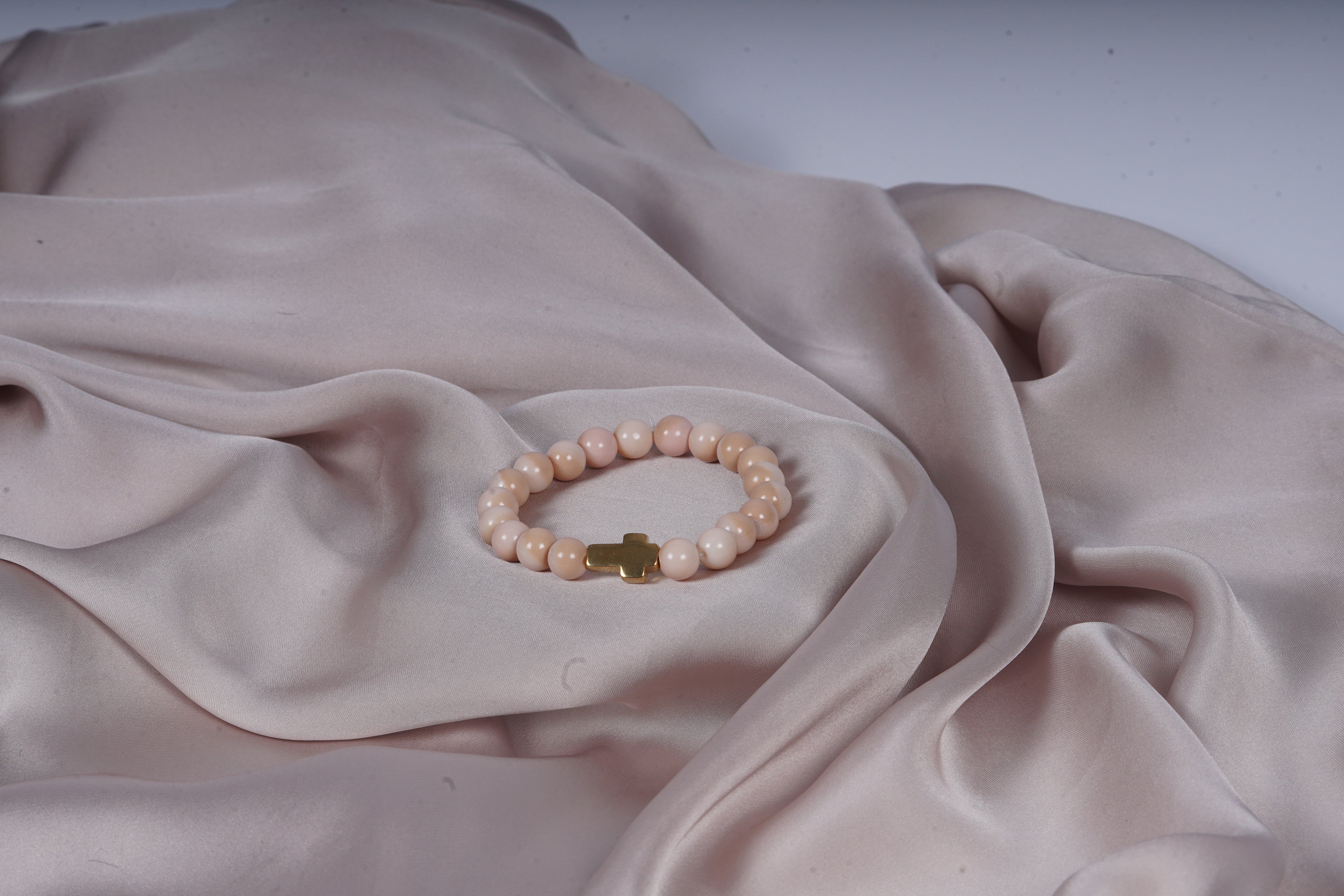 Beige armband met een kruis bedel