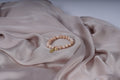 Beige armband met een kruisbedel en een Maria-bedel